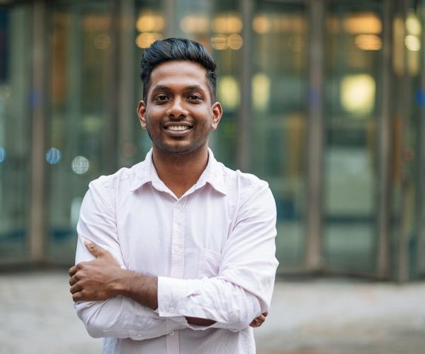 Young businessman smiling with arms crossed.