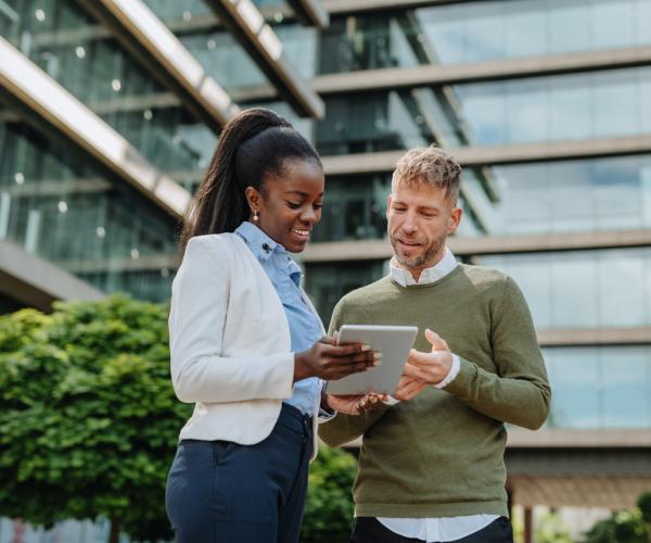 Two people looking at tablet outside a building