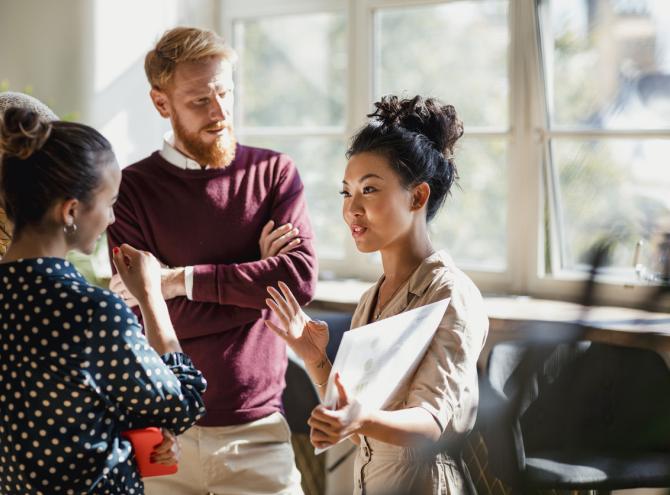 Colleagues standing in a small group discussing something.