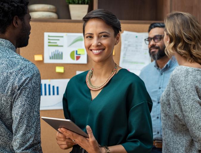 Business woman looking at camera with colleagues working in background.