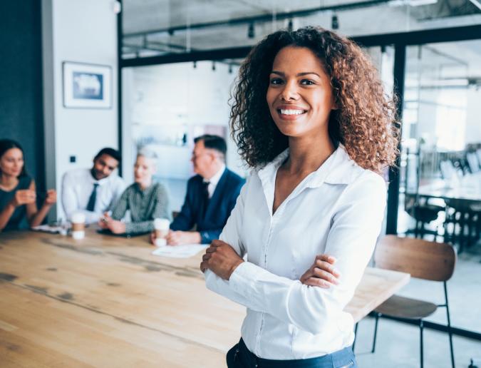Businesswoman standing in conference room with her colleagues in the background