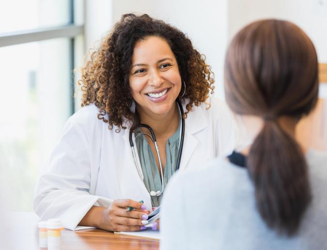 Female doctor listens as a female patient discusses her health.