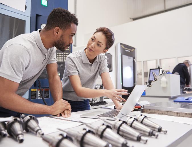 Two engineers using CAD on laptop