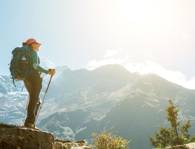 Woman paused while hiking and is looking at mountain range